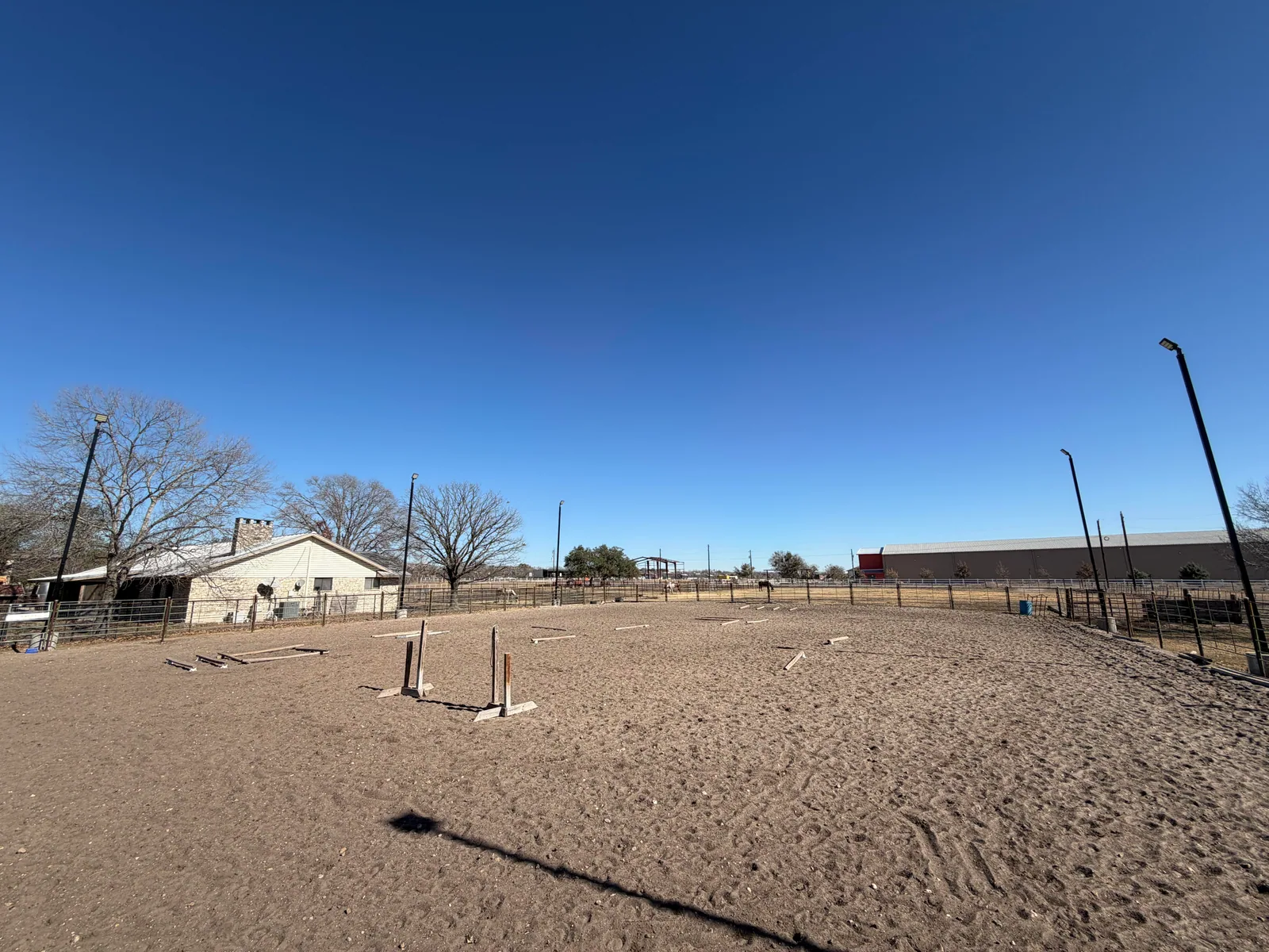 Lighted outdoor sand arena with jump poles